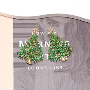 Boucles d'oreilles sapin de Noël avec émail vert et strass colorés sur un magazine