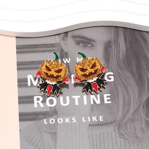 Halloween pumpkin earrings with colorful rhinestones and ghost bat design on magazine