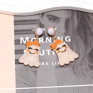Boucles d'oreilles fantômes avec perles et nœuds orange sur un magazine de mode