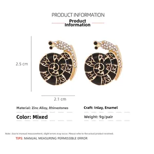 Detail view of gold-tone snail earrings featuring black enamel and white rhinestones