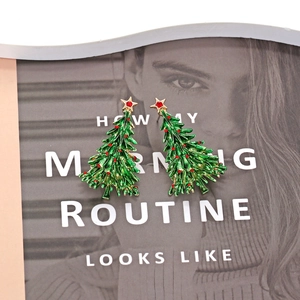 Christmas tree drop earrings with green enamel and gold star on a magazine background