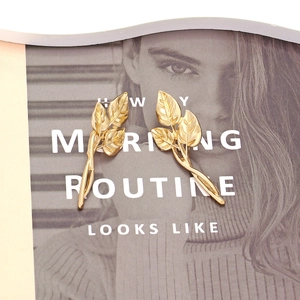 Minimalist vintage gold leaf earrings with intricate vein details on a stylish background
