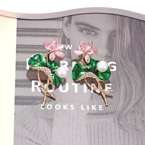 Boucles d'oreilles lotus avec cristaux roses et émail vert sur un magazine mode