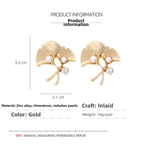 Detailed macro view of gold ginkgo leaf earrings with pearls and rhinestones