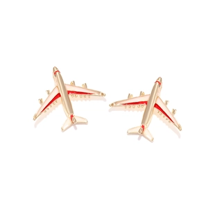Cute gold airplane stud earrings with red and white enamel detailing on white background