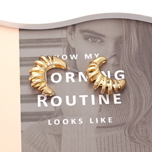 Boucles d'oreilles dorées en C style vintage avec texture spirale sur magazine de mode