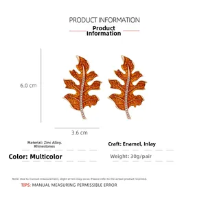 Detail of orange enamel maple leaf earrings with rhinestones showing 6.0cm x 3.6cm size