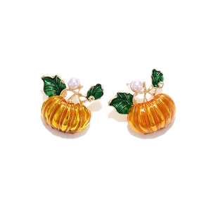 Vibrant orange enamel pumpkin earrings with green leaves and a white pearl accent