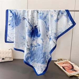 Elegante pañuelo de seda con estampado floral azul y borde azul marino colgado