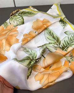 Detalle de bufanda de seda con estampado floral amarillo y mango de metal dorado retro