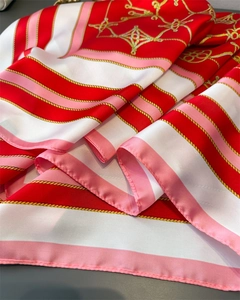 Detail of silk scarf showing vibrant red and gold chain patterns with satin texture