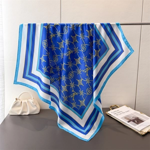 Elegant blue and white silk scarf with gold chain print draped on a metal bar display
