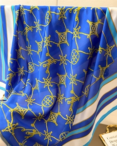 Close-up of elegant blue silk scarf featuring golden rope patterns and satin texture