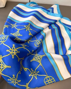 Close-up of luxury silk-like scarf with gold nautical rope patterns and blue satin finish