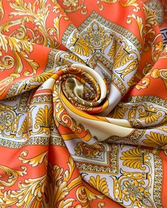Close-up of luxury satin silk scarf featuring orange baroque gold patterns and glossy finish
