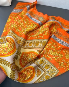 Detail of baroque luxury silk scarf featuring golden patterns and greek key motifs