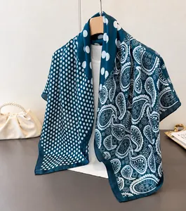 Detail shot of silky paisley and polka dot print scarf draped over a white knit top