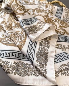 Detailed macro view of beige silk scarf with golden baroque pattern and greek key borders