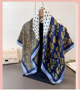 Detailansicht eines Seidenschals mit Paisley- und Punktmuster auf einem Holzbügel