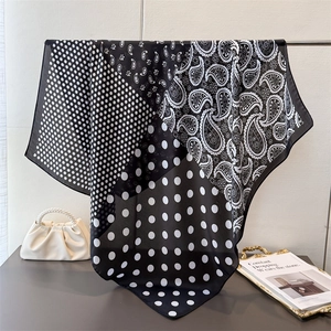 Elegant black and white paisley silk scarf with dots hanging on a metal rack