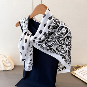 Detail of paisley and polka dot faux silk scarf tied on a hanger with fashion accessories