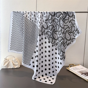 Elegant paisley and polka dot silk-like scarf draped over a stand for stylish women