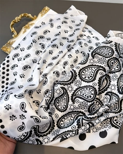Detail of silk-like paisley scarf with black and white patterns on a vintage tray