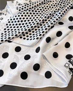 Detailed view of paisley and polka dot print on premium silky white and black scarf