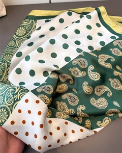 Detail eines Seidenschals mit Paisley- und Punktmuster in kräftigen Grün- und Brauntönen