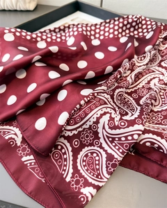 Close-up of wine red silk scarf featuring paisley floral and white polka dot patterns