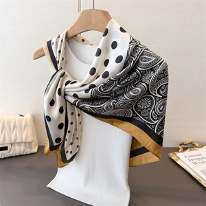 Detail eines Seidenschals mit Paisley-Muster und Punkten an einem Holzbügel