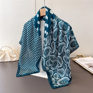 Close-up of a peacock green silk scarf featuring paisley patterns and white polka dots