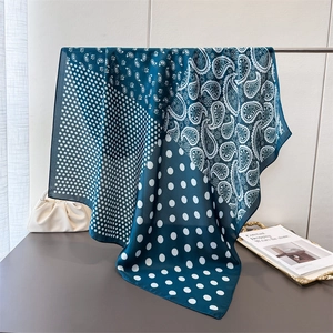 Teal and white paisley print square silk scarf with polka dots hanging on display