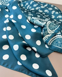 Detail of dark teal silk scarf featuring white polka dots and paisley patterns