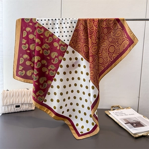 Eleganter Seidenschal mit Paisley- und Punktmuster und Goldrand an Kleiderstange