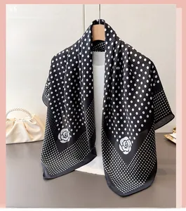 Détail d'un foulard effet soie à pois blancs et imprimé floral sur un cintre en bois