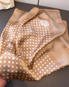 Gros plan d'un foulard en soie à pois blancs et imprimé camélia en marron kaki