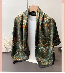 Close-up of a satin silk scarf with green geometric patterns and rolled edge detail