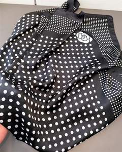 Détail d'un foulard en soie avec motif à pois et imprimé floral de camélia élégant