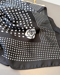 Détail d'un foulard en soie à pois avec motif élégant de camélia blanc raffiné