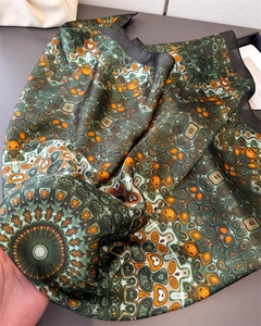 Detail of satin square scarf with geometric kaleidoscope print in green and orange
