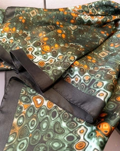 Detail of satin silk scarf featuring vibrant green and orange abstract ring patterns
