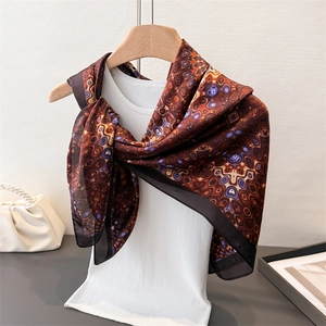 Elegant satin scarf with brown and purple geometric patterns draped over white vest