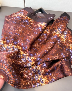 Detail of satin silk scarf featuring bronze and purple abstract geometric patterns