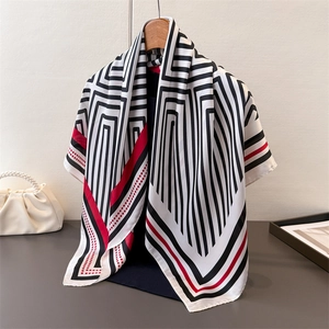 Detail of satin scarf with black and white geometric stripes and red accents on a hanger