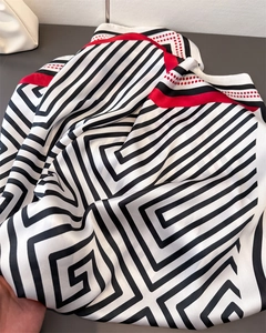 Close-up of geometric striped satin scarf with red border and luxury silk texture