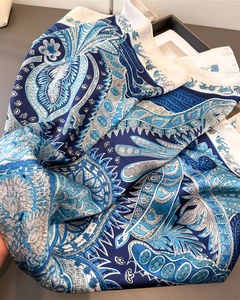 Détail macro d'une écharpe en satin avec motifs paisley bleus et bords roulés raffinés