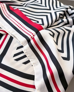 Macro detail showing geometric stripes and red dots on a silky satin scarf fabric