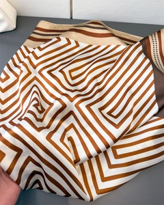 Close-up of geometric striped satin scarf with brown and beige silk-like patterns