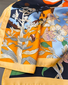 Détail macro du foulard en satin de soie avec imprimé fleurs de lys et bords roulés
